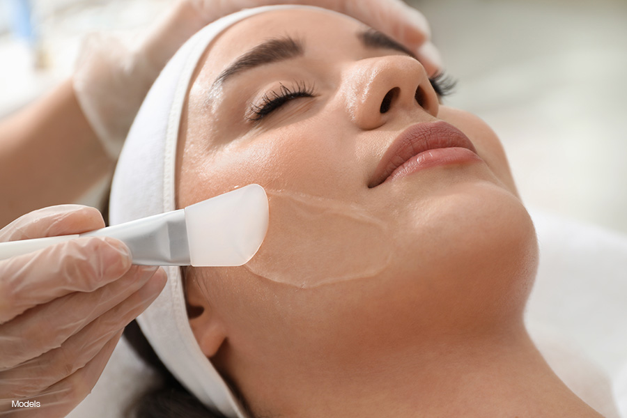 A woman with a white fabric holding her hair back receives a chemical peel.